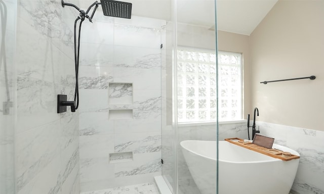 bathroom featuring vaulted ceiling, independent shower and bath, and tile walls