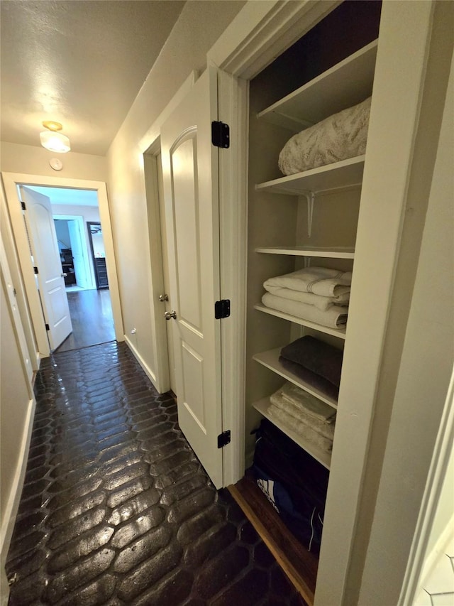 corridor with brick floor and baseboards