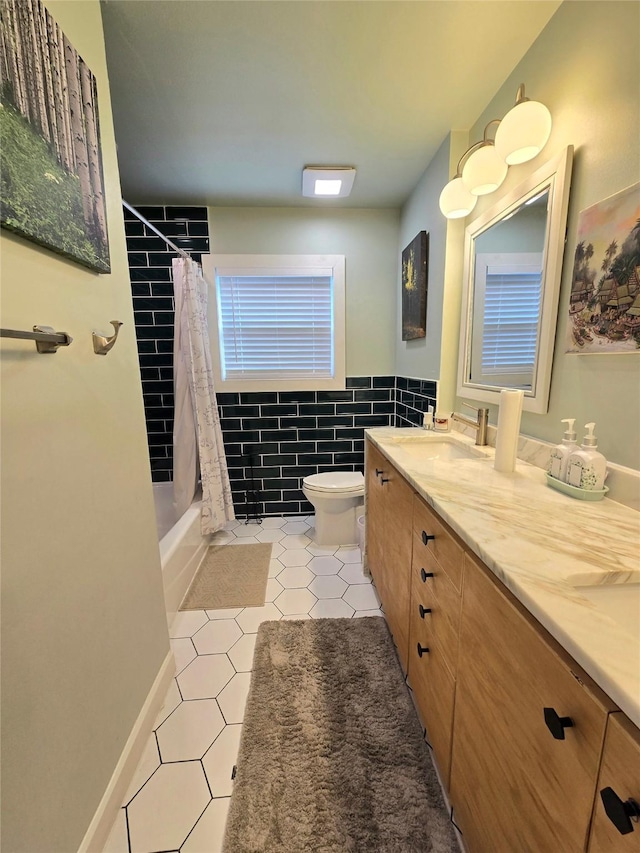 full bathroom with shower / bath combo, toilet, tile patterned floors, vanity, and tile walls