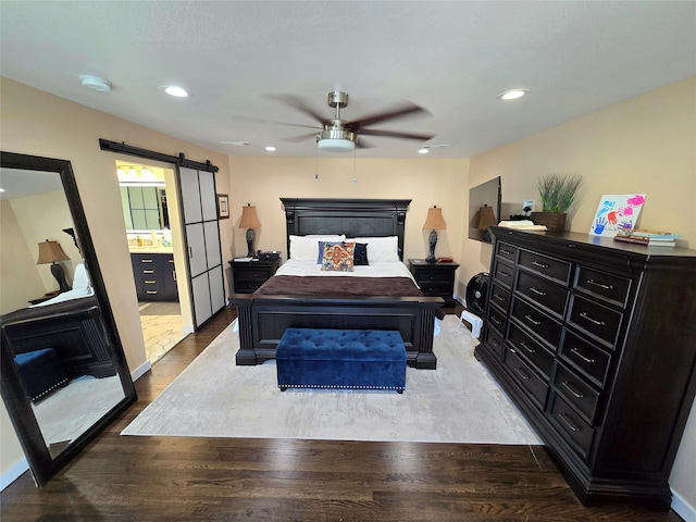 bedroom with recessed lighting, wood finished floors, and a barn door