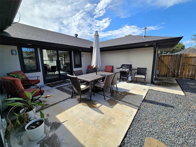 view of patio featuring outdoor dining area, area for grilling, fence, and a gate