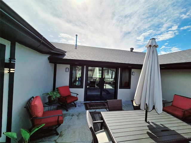 rear view of property with a shingled roof, outdoor dining area, and stucco siding