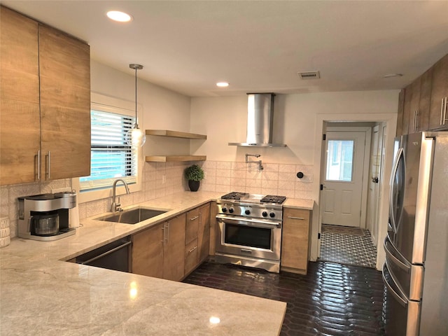 kitchen featuring visible vents, appliances with stainless steel finishes, a sink, wall chimney range hood, and light stone countertops