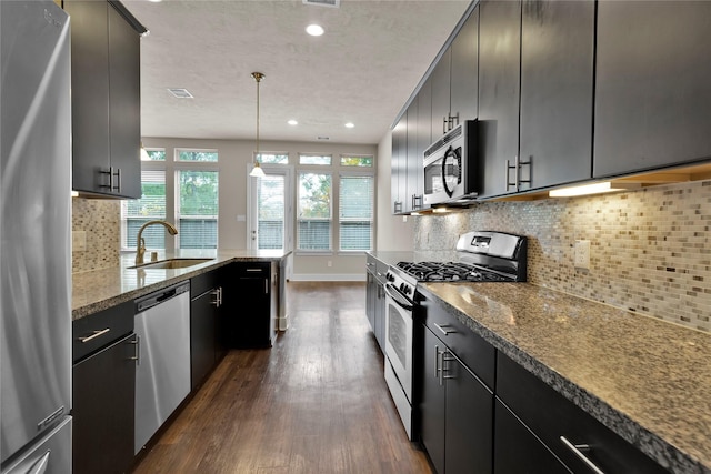 kitchen featuring tasteful backsplash, stainless steel appliances, dark wood-type flooring, sink, and hanging light fixtures