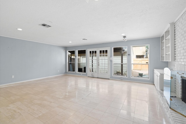 empty room with a fireplace, light tile patterned flooring, and a textured ceiling