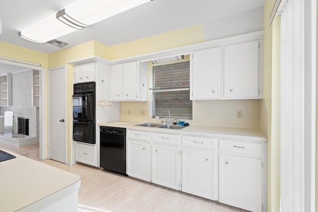 kitchen featuring black appliances, white cabinets, sink, and a brick fireplace