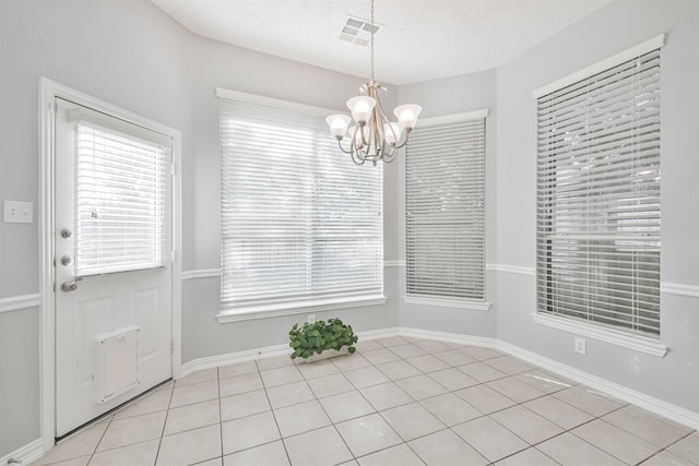 unfurnished dining area featuring a textured ceiling, a notable chandelier, and light tile patterned flooring