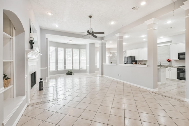 unfurnished living room with light tile patterned floors, a textured ceiling, ceiling fan, and sink