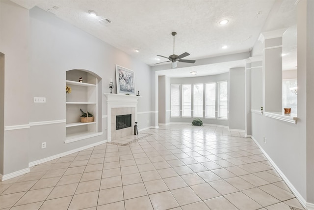 unfurnished living room featuring ceiling fan, built in features, light tile patterned floors, and a textured ceiling