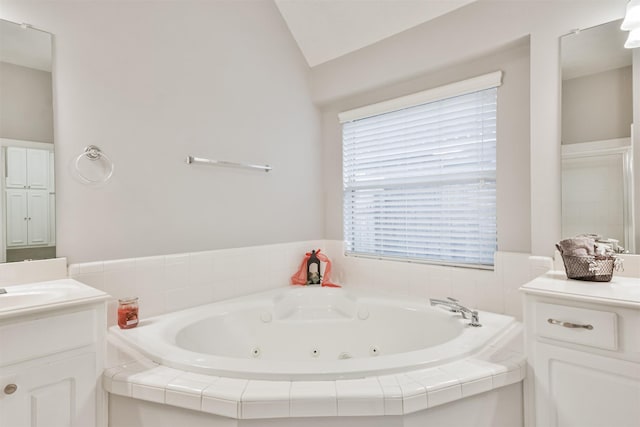 bathroom featuring a relaxing tiled tub, lofted ceiling, and vanity