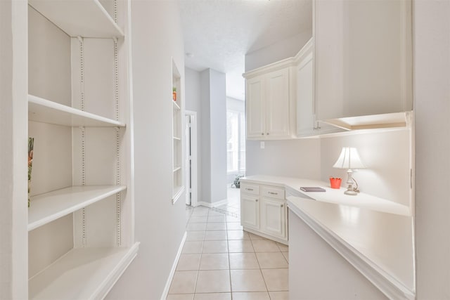 kitchen with light tile patterned flooring, white cabinetry, and a textured ceiling