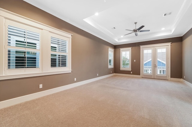 carpeted empty room featuring ceiling fan, crown molding, a tray ceiling, and french doors