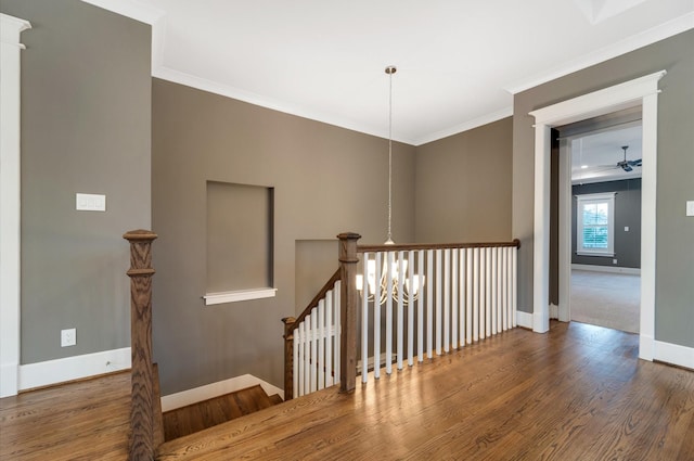 staircase featuring hardwood / wood-style flooring, ornamental molding, and a chandelier