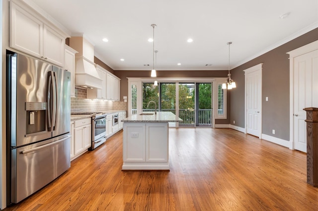 kitchen with pendant lighting, white cabinets, stainless steel appliances, and light hardwood / wood-style flooring