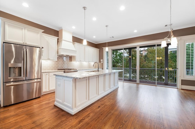 kitchen featuring white cabinetry, stainless steel fridge with ice dispenser, light hardwood / wood-style floors, decorative light fixtures, and custom range hood