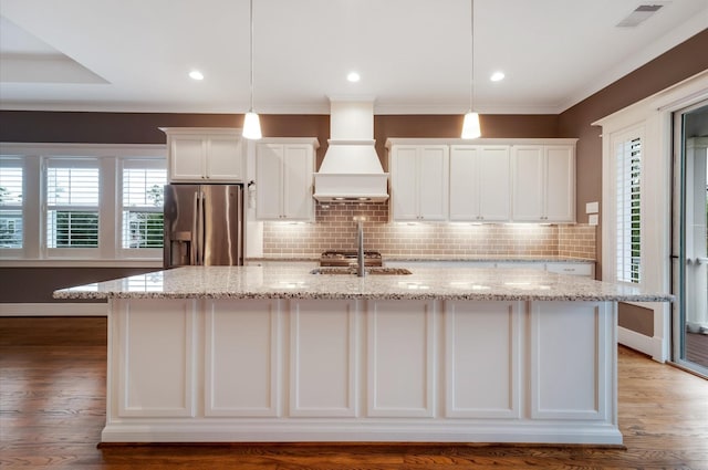 kitchen featuring decorative light fixtures, white cabinetry, stainless steel fridge with ice dispenser, and custom range hood