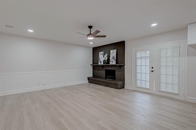 unfurnished living room featuring light hardwood / wood-style floors, ceiling fan, french doors, and a fireplace