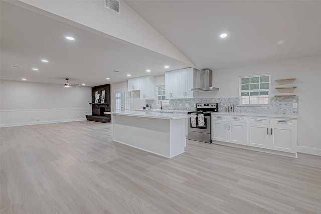 kitchen featuring white cabinets, stainless steel electric range oven, vaulted ceiling, and wall chimney exhaust hood