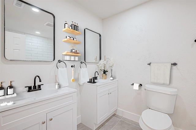 bathroom with toilet, vanity, and tile patterned floors