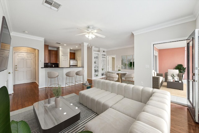 living room with dark hardwood / wood-style floors, ceiling fan, crown molding, and built in shelves