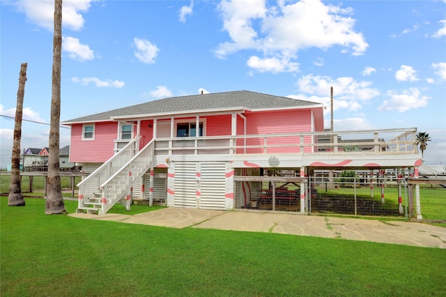 rear view of property featuring stairway, a lawn, and roof with shingles