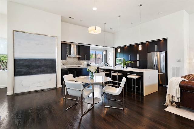 dining room with dark wood-style floors, visible vents, and a high ceiling