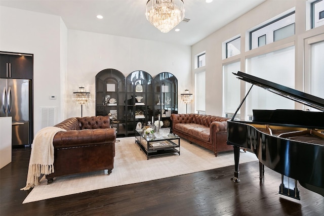 living room featuring hardwood / wood-style floors, a towering ceiling, and a notable chandelier