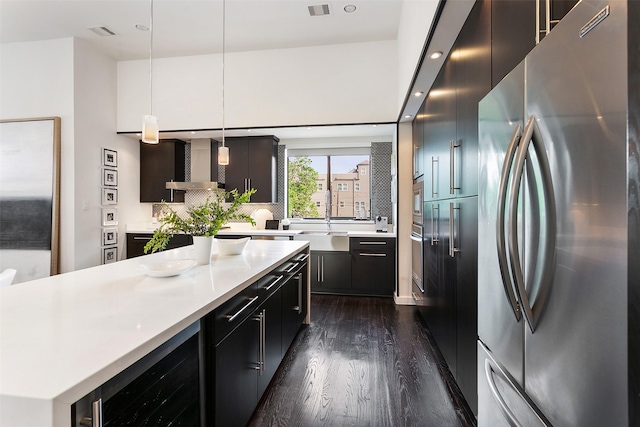 kitchen featuring wall chimney exhaust hood, stainless steel appliances, sink, pendant lighting, and wine cooler