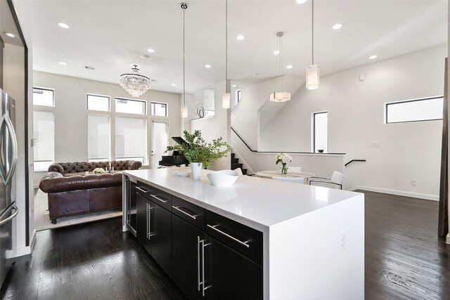 kitchen featuring a center island, an inviting chandelier, dark hardwood / wood-style flooring, stainless steel fridge, and decorative light fixtures