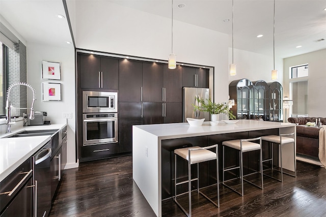 kitchen featuring a breakfast bar, dark wood-type flooring, a kitchen island, dark brown cabinetry, and stainless steel appliances