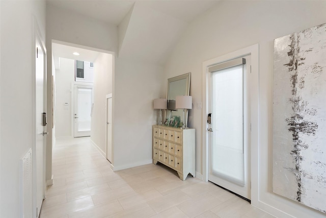 hall featuring light tile patterned floors and lofted ceiling