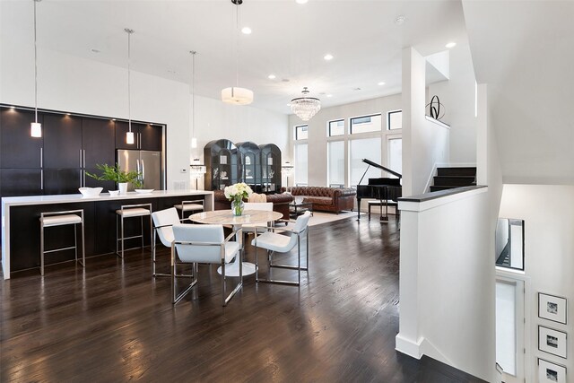 dining room featuring a chandelier, a towering ceiling, and dark hardwood / wood-style floors