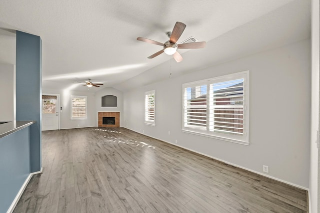 unfurnished living room featuring ceiling fan, a fireplace, lofted ceiling, and hardwood / wood-style flooring