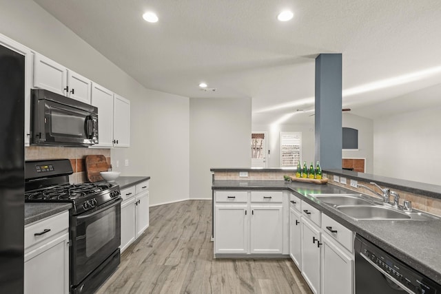 kitchen featuring sink, light hardwood / wood-style flooring, kitchen peninsula, white cabinets, and black appliances