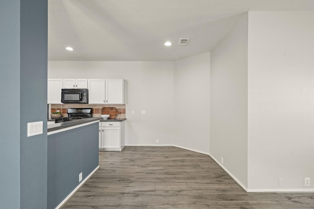 kitchen featuring backsplash, hardwood / wood-style floors, white cabinets, and black appliances