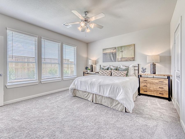 carpeted bedroom with ceiling fan and a textured ceiling