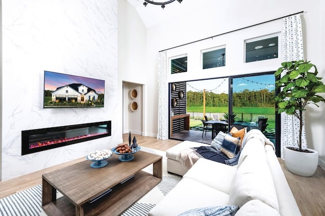 living room with a tile fireplace, hardwood / wood-style floors, and a high ceiling