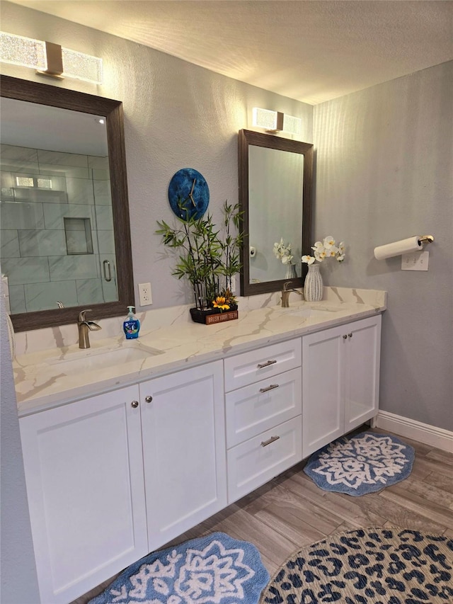 bathroom with hardwood / wood-style floors, vanity, an enclosed shower, and a textured ceiling