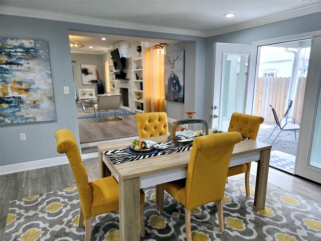 dining space with hardwood / wood-style floors, ornamental molding, and a fireplace