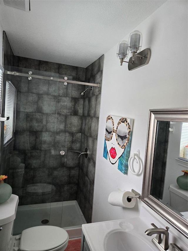 bathroom with an enclosed shower, vanity, toilet, and a textured ceiling