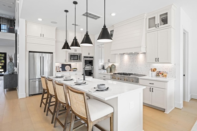 kitchen with appliances with stainless steel finishes, white cabinetry, and an island with sink