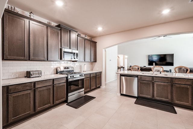 314 Polar Bear Trl, Crosby, TX 77532 - kitchen featuring stainless steel appliances, arched walkways, dark brown cabinets, open floor plan, and tasteful backsplash