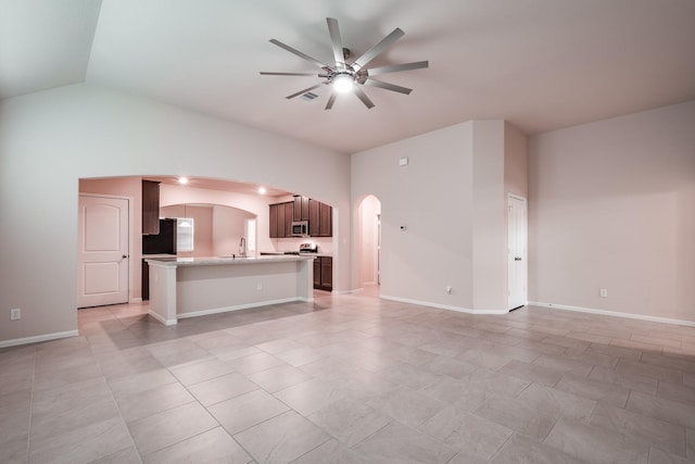 unfurnished living room featuring ceiling fan, sink, light tile patterned floors, and lofted ceiling