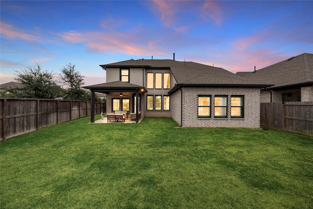 back house at dusk featuring a yard, an outdoor living space, and a patio