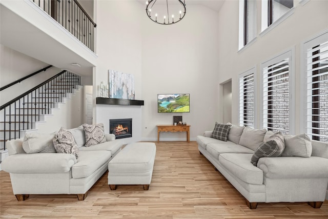 living room with a chandelier, light hardwood / wood-style floors, and a towering ceiling