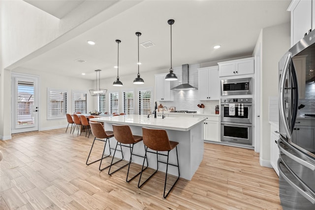 kitchen featuring appliances with stainless steel finishes, wall chimney exhaust hood, and white cabinets