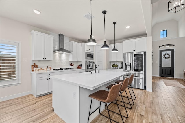 kitchen with white cabinetry, wall chimney exhaust hood, and stainless steel appliances