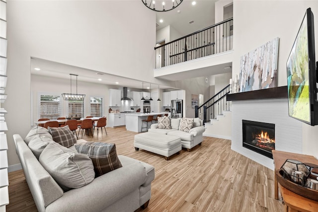 living room with a towering ceiling, an inviting chandelier, and light hardwood / wood-style floors