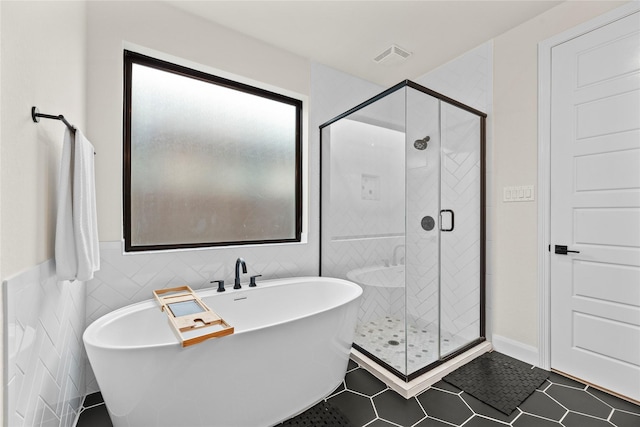 bathroom with plus walk in shower, tile walls, and tile patterned floors