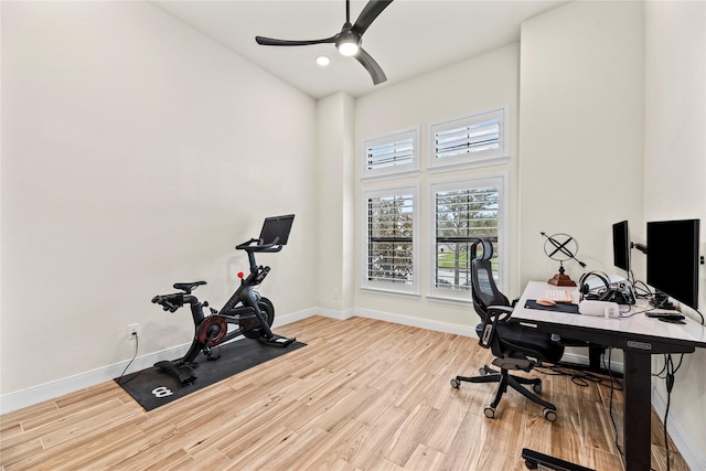 office space with ceiling fan, light hardwood / wood-style floors, and a towering ceiling